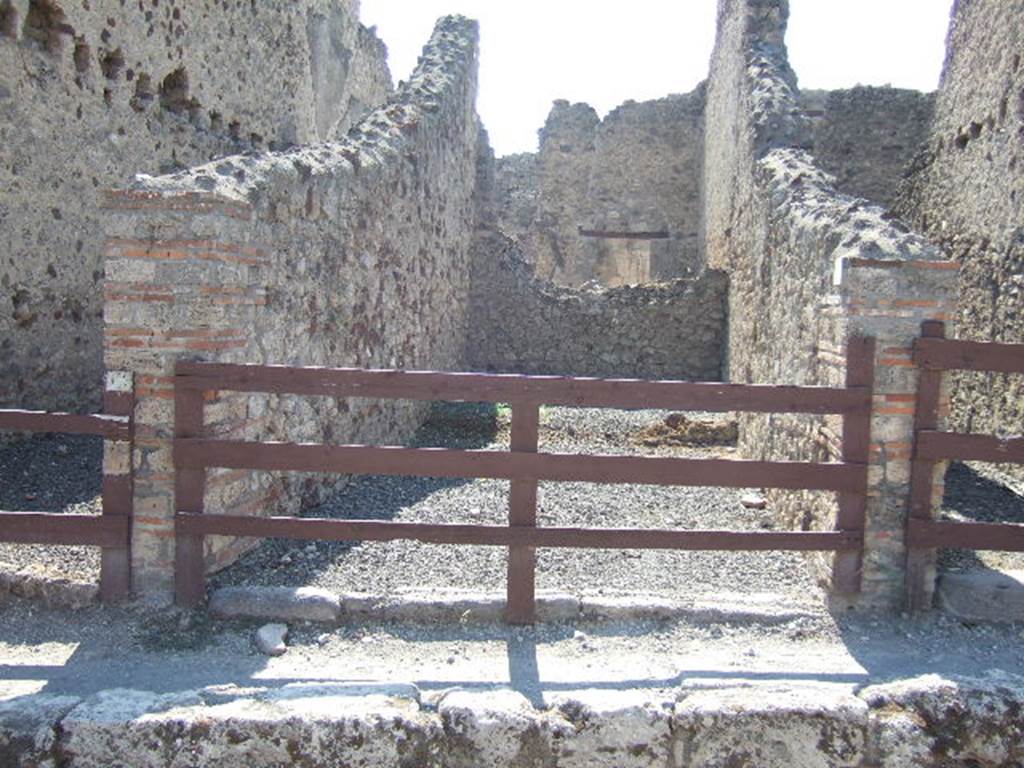 VI.14.26 Pompeii. September 2005. Looking west towards entrance doorway of workshop with a small rear room. According to BdI, the rear room was simply painted and reached by two steps in the middle of the west wall of the shop. To the right of these steps was the latrine. On the left was a large cauldron (deep 0.60 x 0.75 diam) embedded in a masonry structure, and under this the place for the fire, open at the front. Found here was a flagon and a casserole, both of bronze, a tripod that held a terracotta bowl, three dies (as in a game of dice), and four bronze coins. (18th May 1875). One could conclude that here was a thermopolium. See BdI, 1876, (p.45).