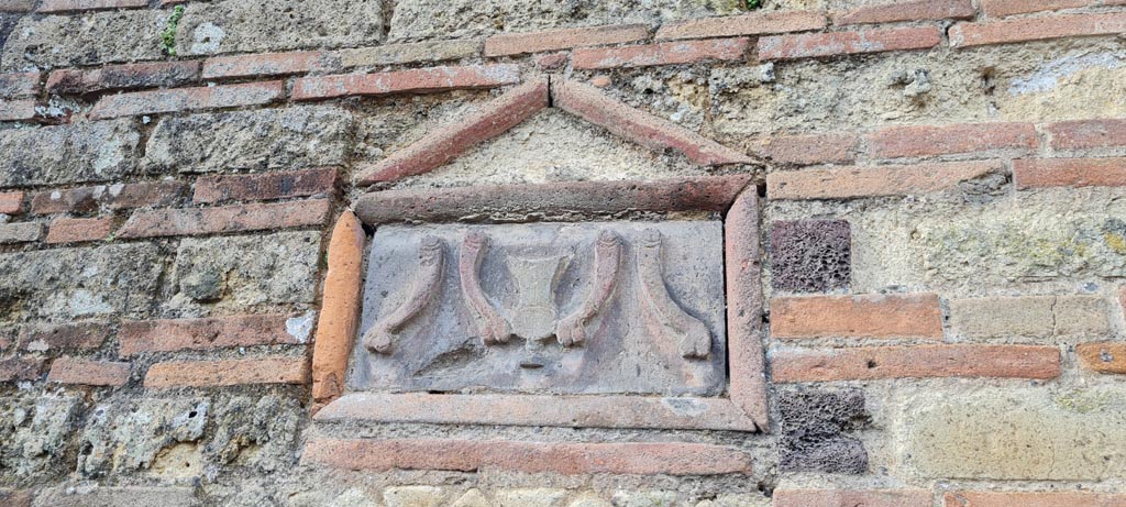 VI.14.28 Pompeii. April 2022. 
Terracotta plaque on front façade on south side of entrance doorway. Photo courtesy of Giuseppe Ciaramella.