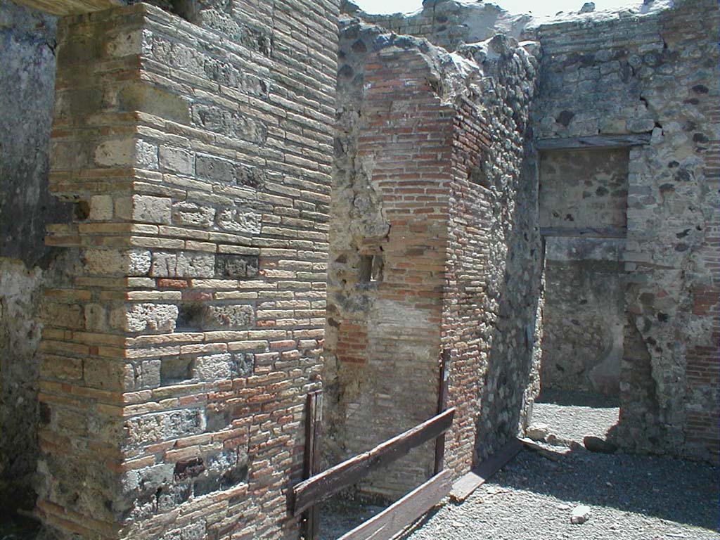 VI.14.30 Pompeii. May 2005. Looking south along east side of atrium.
The entrance corridor or fauces is in the centre, the doorway into VI.14.28 is on the right.