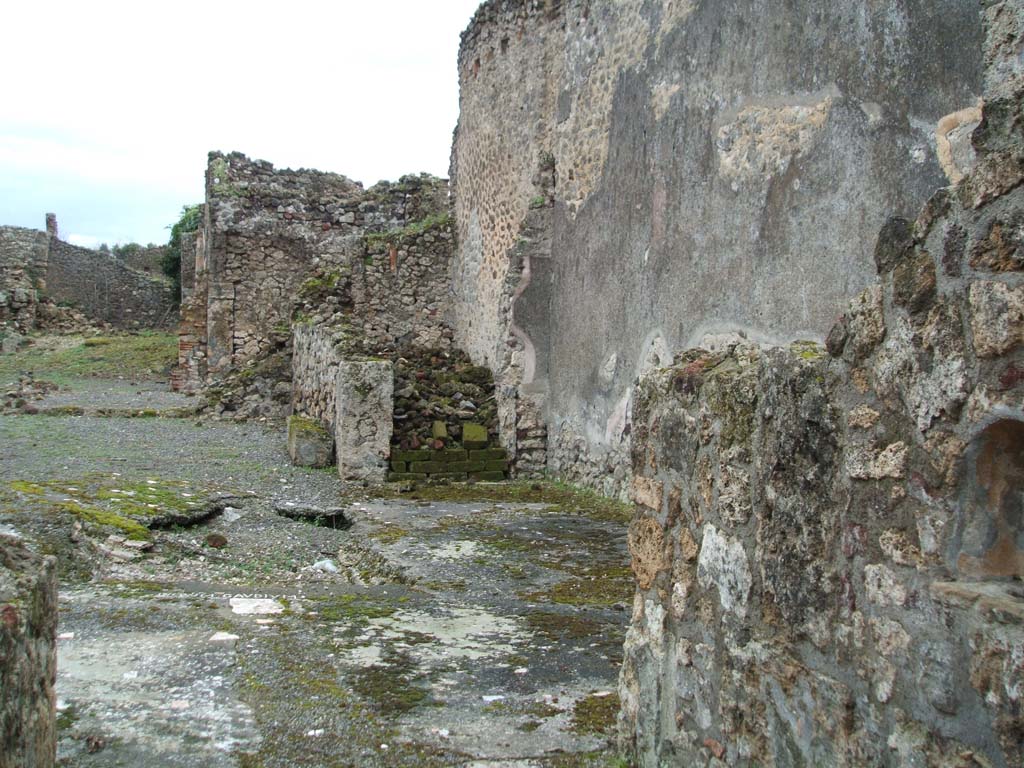 VI.14.39 Pompeii. December 2004. 
Looking east from entrance doorway, across atrium and tablinum, garden area, and exedra at the very rear overlooking the garden. 
According to Garcia y Garcia, the same bomb that damaged the previous house also brought down this one.
It now appears completely ruined.
The dividing wall between VI.14.38 and 39 does not exist anymore.
Of the two staircases, one going up to the first floor, the other going down to the basement, no traces remain.
The IV Style painted plaster also perished. 
See Garcia y Garcia, L., 2006. Danni di guerra a Pompei. Rome: L’Erma di Bretschneider. (p.93-4, incl. photos by Tatiana Warscher).
According to Jashemski, the small garden (approximately the green area on the left of the above photo) had a narrow portico.
This portico on the north was supported by two columns and an engaged column.
The terrace, or loggia, was on the east side. The exedra was at the eastern rear side of the terrace, and overlooked the garden.
Both the terrace and exedra were 0.95m above the garden and could be reached by four steps.
Another set of steps on the left (north) led to a basement area.
Another roof covered the terrace and steps.
There was a terracotta puteal near the two columns in the garden.
Also found near the south wall was a circular basin of grey marble, supported by a cylindrical foot of cipolin.
See Jashemski, W. F., 1993. The Gardens of Pompeii, Volume II: Appendices. New York: Caratzas. (p.151)