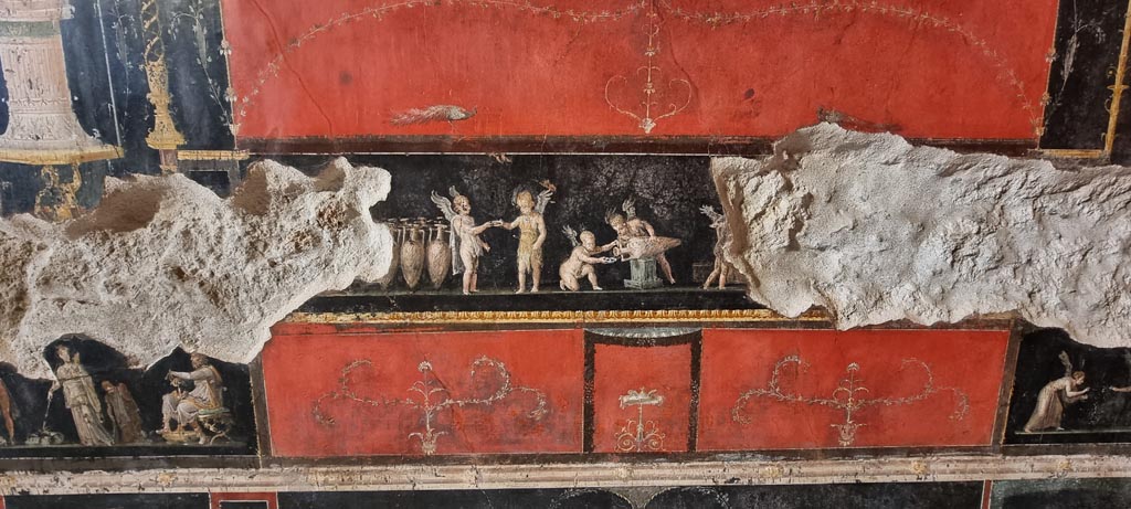 VI.15.1 Pompeii. January 2023.
Central panel in predella on west wall, with painting of cupids buying and selling wine. Photo courtesy of Miriam Colomer.