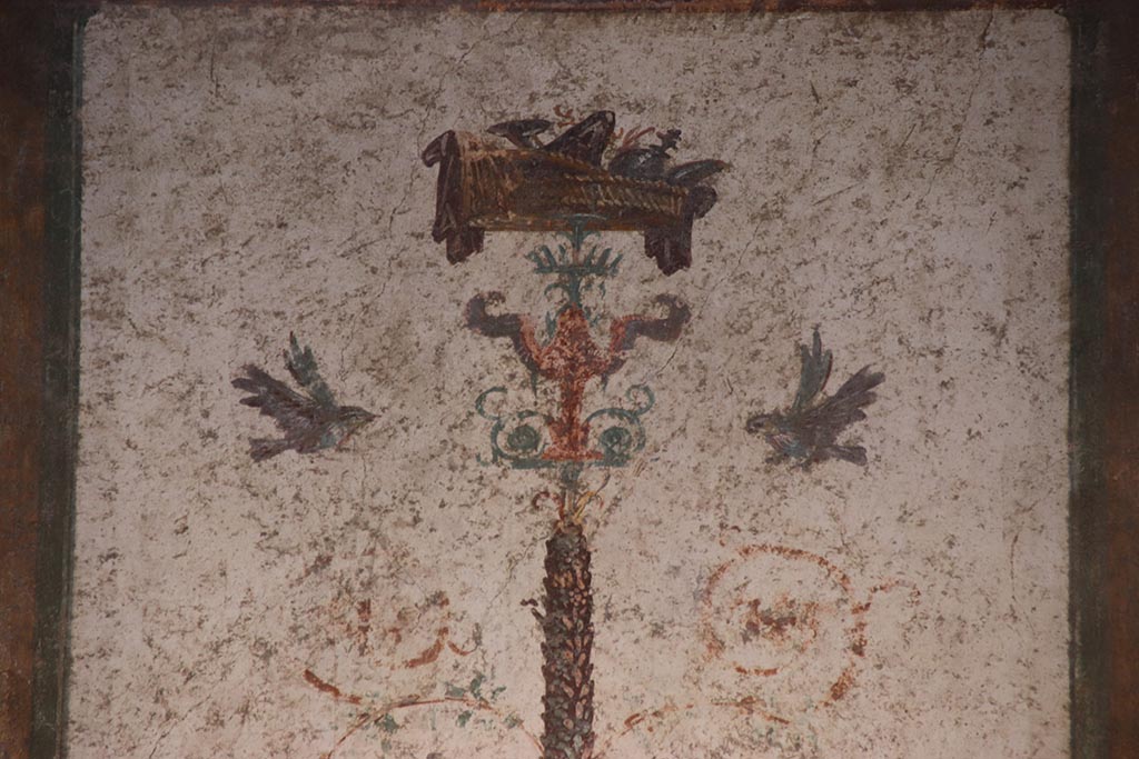 VI.15.1 Pompeii. October 2024.
Cubiculum g, detail of painted decoration on top of candelabrum in centre of north wall. Photo courtesy of Klaus Heese.