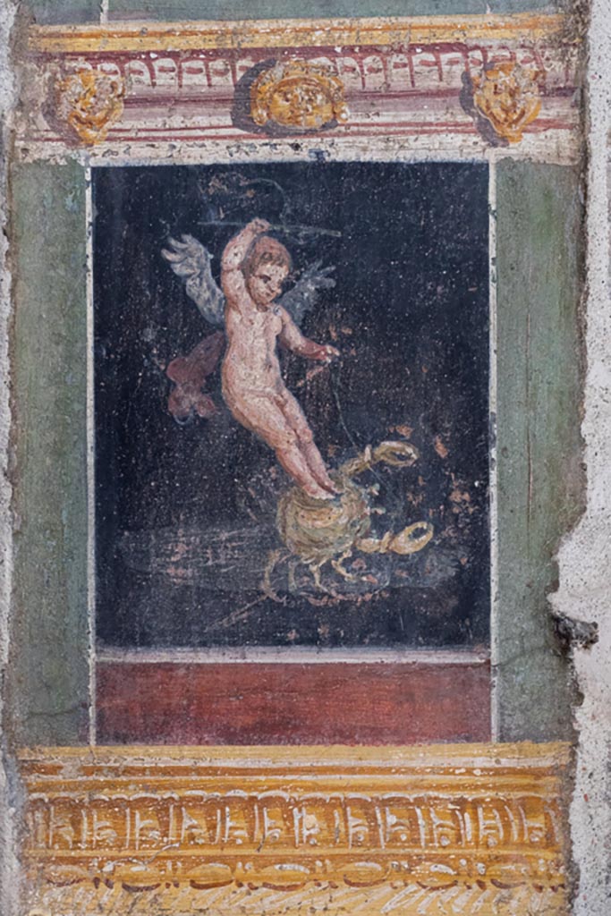VI.15.1 Pompeii. March 2023.
Detail of painted panel with cupid on crab on south end of west wall of atrium, leading onto peristyle.
Photo courtesy of Johannes Eber.