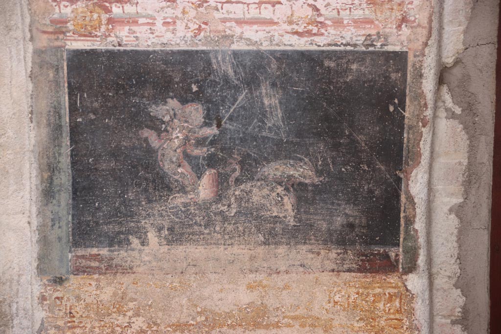 VI.15.1 Pompeii. October 2023.
East wall of atrium, detail of cupid and dolphins from panel between entrance corridor and cubiculum on south side of entrance.
Photo courtesy of Klaus Heese.