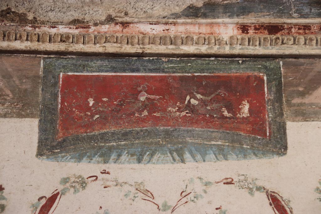 VI.15.1 Pompeii. October 2023.
Detail of painted panel from above the central “removed” missing painting on east wall. Photo courtesy of Klaus Heese.