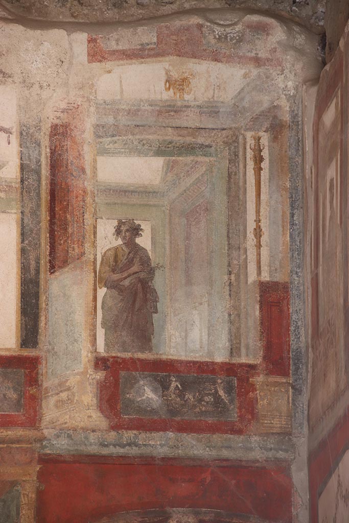 VI.15.1 Pompeii. October 2024.
Upper east wall of exedra, painted figure with panel below, from south end of east wall.
Photo courtesy of Klaus Heese.