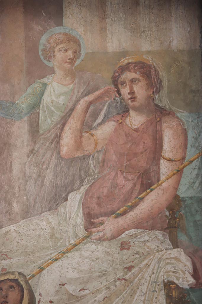 VI.15.1 Pompeii. October 2023. Detail of Juno and long stick/baton against right arm.
Hera/Juno with gold crown and long sceptre is seated on her throne with Iris standing to her left, gesticulating.
Photo courtesy of Klaus Heese.