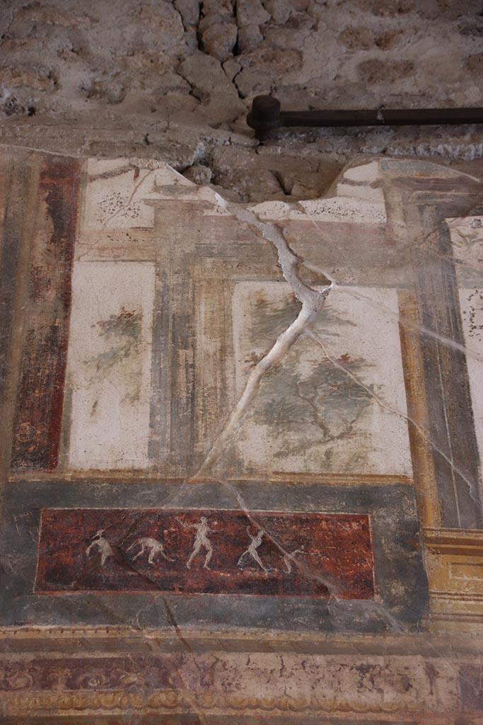 VI.15.1 Pompeii. October 2024.
Upper south wall, painted decoration with panel below, on east side of central figure.
Photo courtesy of Klaus Heese.