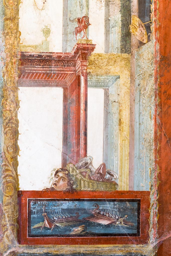 VI.15.1 Pompeii. March 2023.
North wall of exedra, from east side of central painting, panel with naval scene with mask and basket above.
Photo courtesy of Johannes Eber.