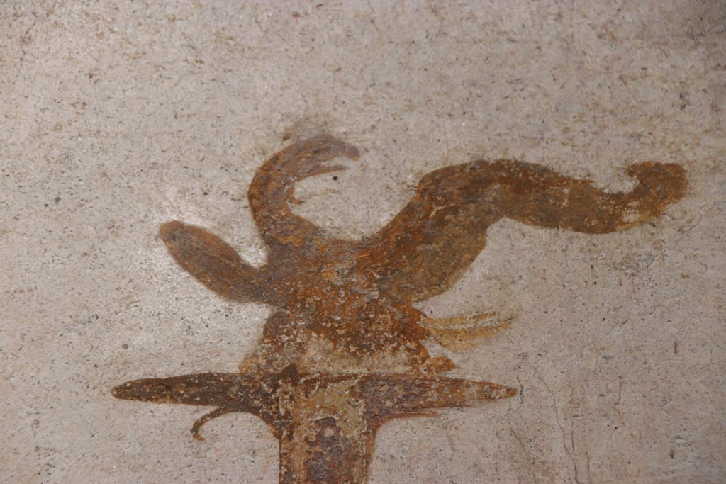 VI.15.1 Pompeii. October 2023.
North wall of small courtyard/peristyle garden “s”, detail of painted eagle from top of candelabra. Photo courtesy of Klaus Heese.
