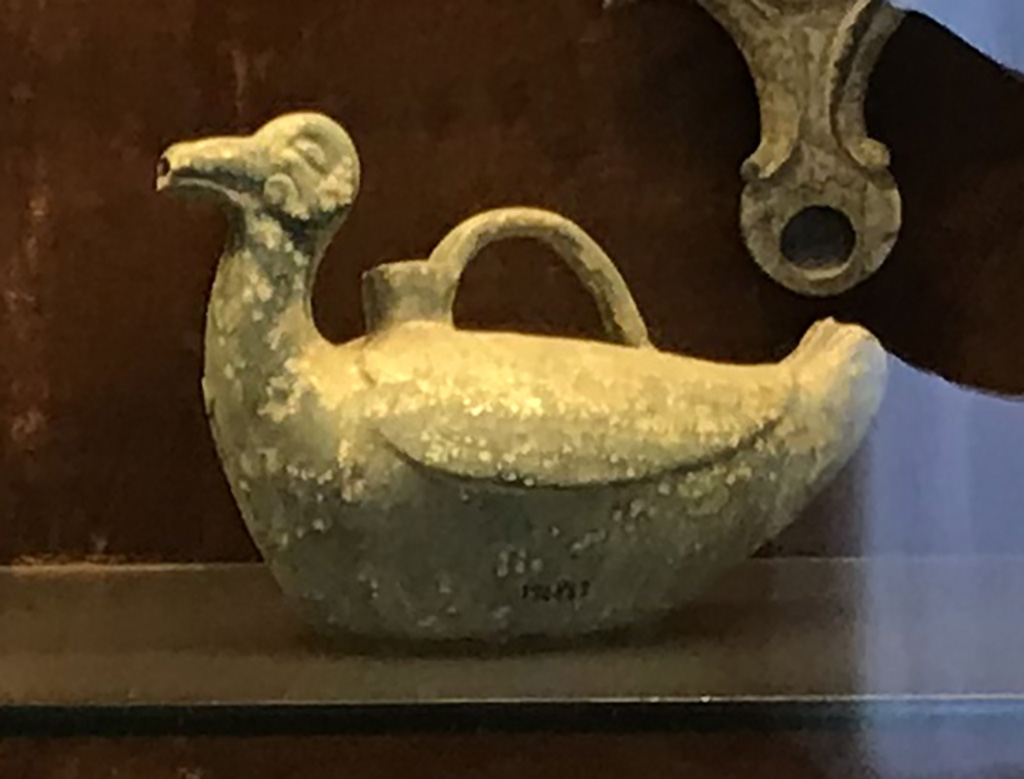 VI.15.5 Pompeii. April 2019. 
Pot/jug/vase in the shape of a duck, found on west side of garden near the aedicula. Photo courtesy of Rick Bauer.
Now in Naples Archaeological Museum, inventory no. 124842.
Sala (room) 88, glass cabinet II, shelf B (middle).
Also found with this was a pot/jar/vase in the shape of a bird (inv. 124848), the group of Pero and Mikon (inv.no.124846) and a statue of Silenus (inv.no. 124847   cat 7.1) 
See Di Gioia, E. (2006). La ceramica invetriata in area vesuviana. “L’Erma” di Bretschneider, (p.61).