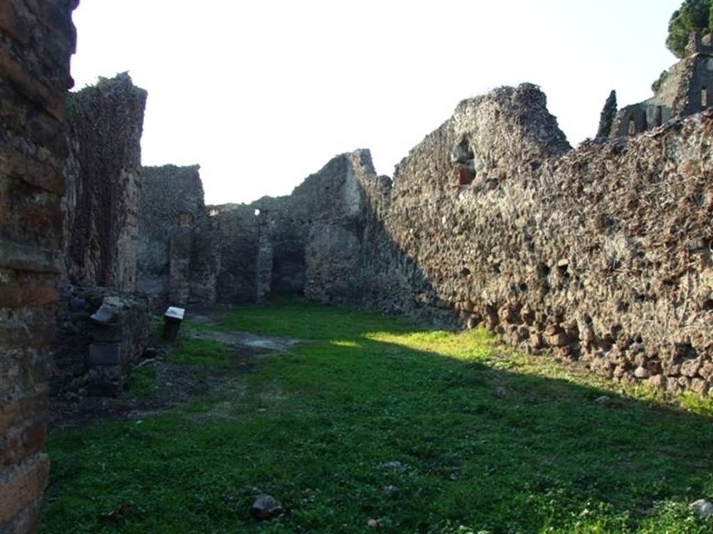 VI.15.18 Pompeii. December 2007. Looking west from entrance.
According to Boyce, this was an irregular building which was undergoing alterations at the time of the eruption. Its purpose was not clear, perhaps the large central room was used for housing carts. The walls seem to have been all undecorated except for those in a long narrow room in the south-west corner. In the south end of that room, a domestic sacellum was built. The sacellum had a vaulted ceiling and a floor of pounded sherds, and according to Mau dated from the period of the First Style. Against the south wall stood a masonry altar with concave upper surface. It was coated with white stucco and upon its front side was painted a small flaming altar with a large serpent on each side. Near to it on the east wall was a small niche, on the white background of the rear wall was a painted figure. The figure was clad in a blue garment and reclining upon a couch. The rear and side walls of the niche were adorned with painted red leaves and three quinces.
In the room to the north, through which access to this sacellum was gained, on the east wall was a rectangular panel of white stucco.
Within the panel was set a tiny niche for a lamp. Above the panel of white stucco was a second niche coated with coarse plaster and having a painting done in red, on the rear wall. This painting was very poorly preserved but seemed to represent an aedicula and within it an altar.
Not. Scavi, 1897, 463, photograph p.464. See Boyce G. K., 1937. Corpus of the Lararia of Pompeii. Rome: MAAR 14.(p.56, no.218)