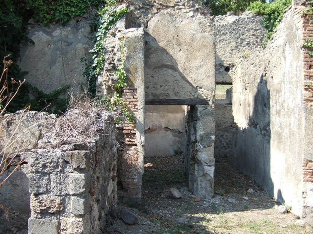 VI.15.20 Pompeii. September 2005. Looking north from atrium, towards doorways to triclinium, centre, and corridor leading to kitchen and latrine, on the right. According to NdS, the corridor had walls faced with white and coarse plaster. The doorjambs of the doorway to the triclinium had portions of red plaster, covered in the last years by other rustic facing of lime. The walls were faced with brick plaster (laterizio), in the west wall were two small windows overlooking the vicolo. In the east wall was a rectangular recess, faced with red plaster. In the excavated earth, a piece of red plaster was retrieved with the figure of a flying psyche (0.16m), and a graffito: PLATOR.
On the pilaster dividing between the triclinium and corridor, Sogliano could read a graffito on the black dado: 
IIROS
IIVRVS
See Notizie degli Scavi, June 1897, (p.274-5)