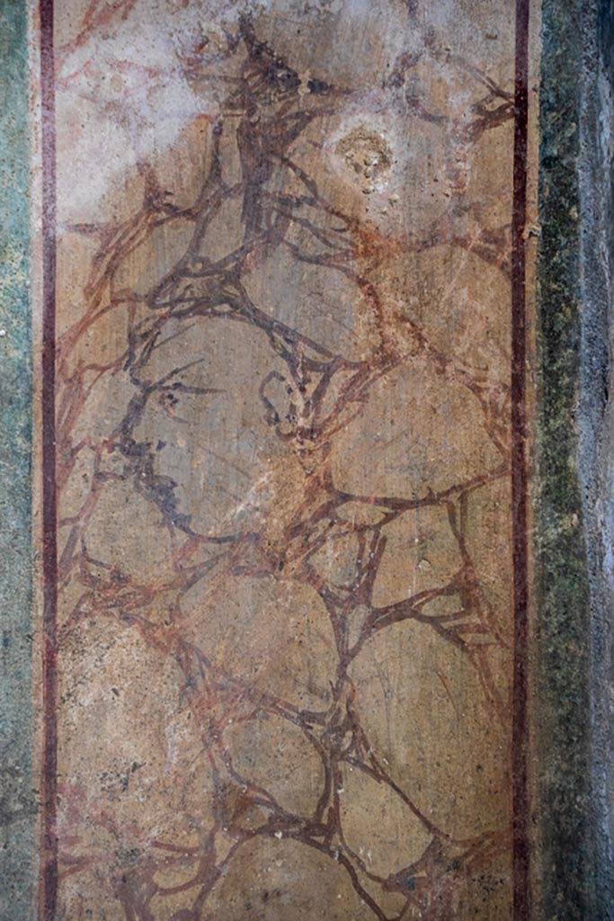 VI.16.7 Pompeii. October 2023. Room F, north portico. Household lararium.
Head outlined in black in painted marble on east side of base.
Photo courtesy of Johannes Eber.