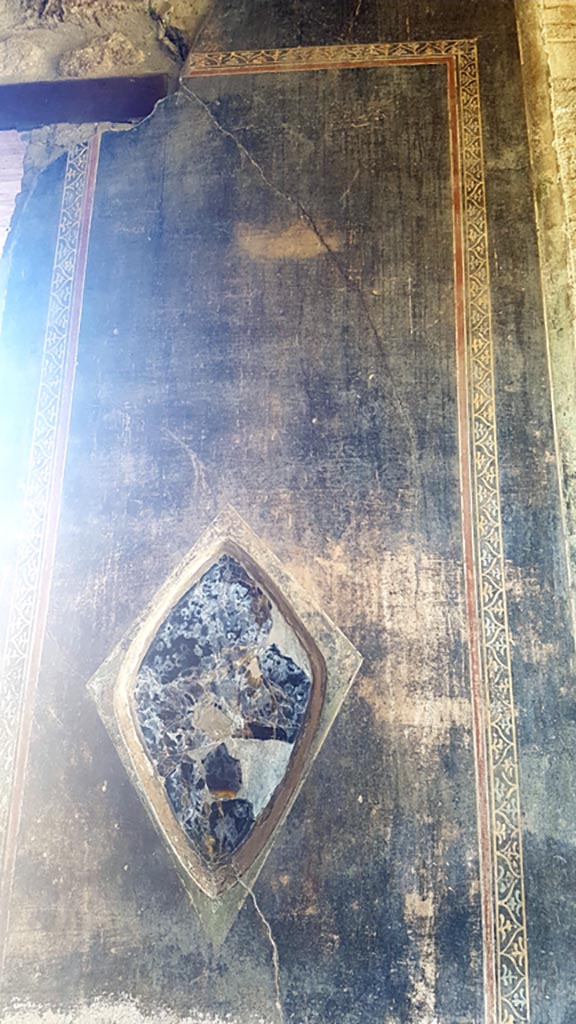 VI.16.7 Pompeii. August 2023. 
Wall decoration and obsidian mirror in north-east corner of portico.
Photo courtesy of Maribel Velasco.