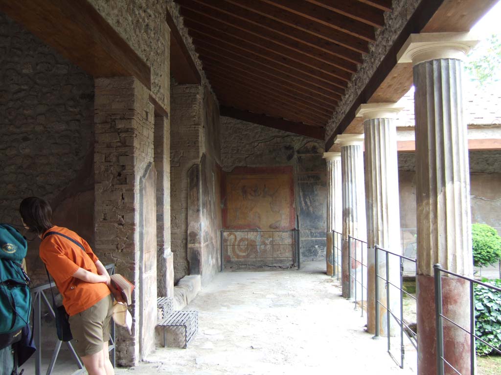 VI.16.7 Pompeii. May 2006. Room F, east portico.  Looking south towards the lararium. 
Nearest on the east wall is the doorway to room G.
Next is the entrance to the long, tall, narrow area 01 with metal steps.  
This had the stairs to the upper floor over room G and the shop at VI.16.6.  
The third entrance with a stone sill is the open area 03 that contained a cupboard.
