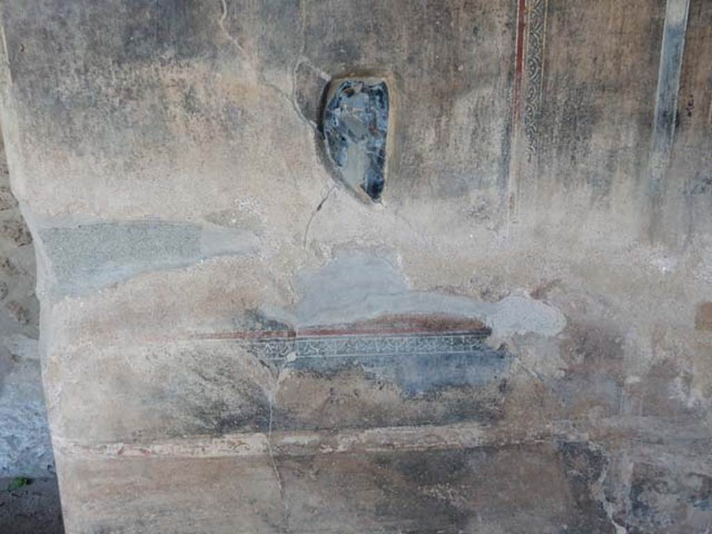 VI.16.7, Pompeii, May 2018. 
Peristyle F, Obsidian mirror embedded in plaster of east wall of east portico at the southern end between the shallow space and the lararium.
Photo courtesy of Buzz Ferebee.