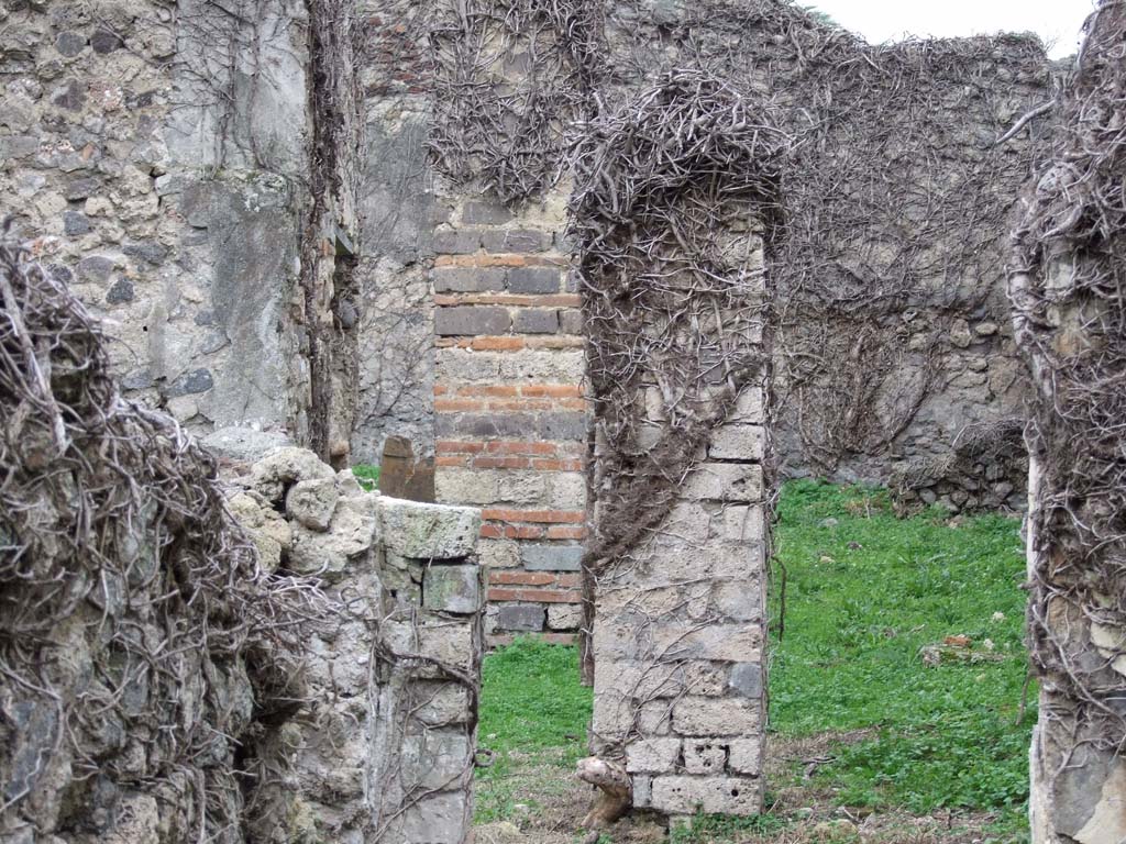 VI.16.10 Pompeii. December 2007. Looking west from triclinium, or cubiculum, across towards rear of house into garden, F.
The pillar, centre left, would have been on the right side of the entrance to the garden area.
It was made of brick and tufa-stone cut into bricks, which were very robust, having to support a roof in F.
The outdoor area F was found with the remains of II style decoration on the north and west walls.
To the left of the brick and tufa pillar, a doorway can be seen. This would have led to the kitchen and latrine.
The other pillar, centre of photo, would have been the one on the north side of the doorway from the corridor.