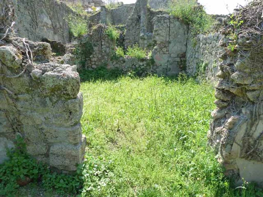 VI.16.11 Pompeii. May 2010. Doorway to rear room in north-west corner of shop. Looking west. According to NdS, the doorway would have had doorjambs and a threshold of wood.
The floor was made of opus signinum but was poorly preserved. The walls were divided into large red panels, divided by yellow pilasters or fillets, with feeding birds in the middle, a flying swan, and a rectangular painting with faded representation. The dado was red but also badly preserved. The frieze had a white background. The remains of the white frieze were still visible upon excavation, in the height of the west wall, in which there was a window. See Notizie degli Scavi di Antichità, 1908, p. 59.