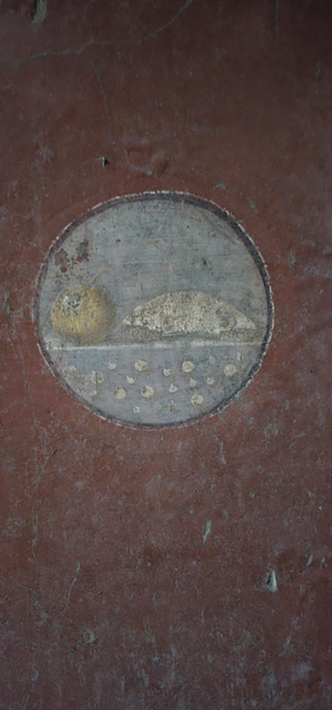 VI.16.15 Pompeii. December 2023.
Medallion on south end of east wall of room F with painting of food.
Photo courtesy of Miriam Colomer.