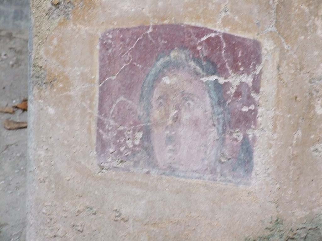 VI.16.15 Pompeii. December 2006. 
Atrium B, between doorway to room E and room D at base of wall. Detail of wall painting of face or mask.