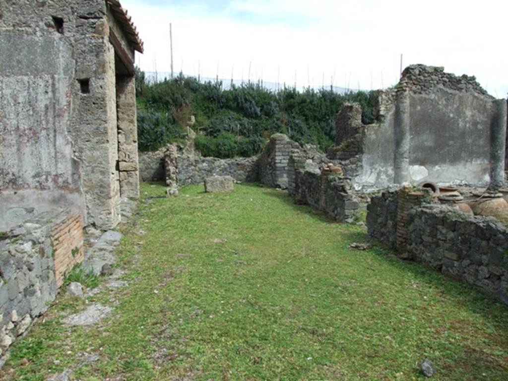 VI.16.27 Pompeii. March 2009. Looking east across north portico.
According to Jashemski, the peristyle garden had a wide portico on the north.  The portico was supported by three columns and one engaged column, covered with rough plaster, red at the bottom.  They were connected by a low masonry wall with an entrance into the garden between the first and second columns, from the east.  Numerous dolia and large jars were found embedded in the soil in the north-east corner of the garden.  See Jashemski, W. F., 1993. The Gardens of Pompeii, Volume II: Appendices. New York: Caratzas. (p.164)