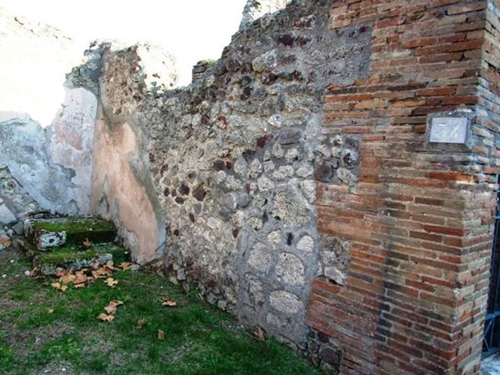 VI.16.34 Pompeii. December 2007. South wall. The shop had a high dado of brick plaster, divided into large panels, by means of vertical red bands. In the centre of each panel was seen  the representation of a plant with a very high stem. In the south-east corner is a rise of masonry with two steps, on which rested a wooden ladder leading to the upper floor.
The imprint of the ladder can be seen on the east wall. The floor was of coarse cocciopesto.