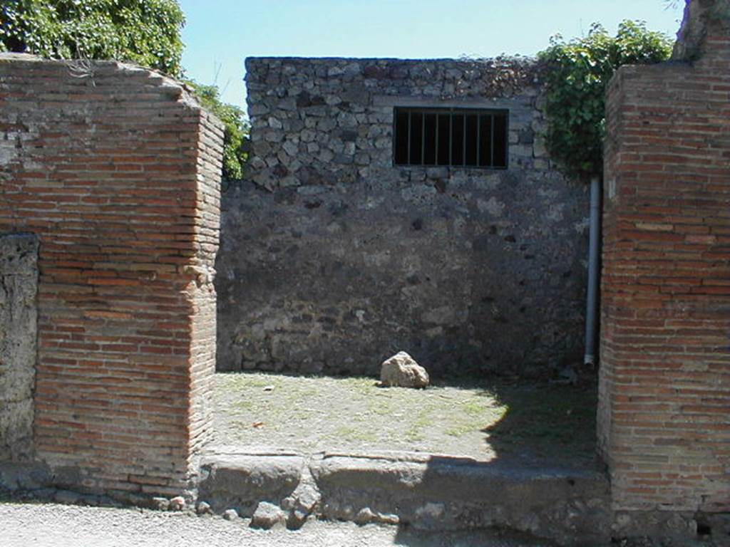 VI.16.37 Pompeii. May 2005. Looking east to shop entrance doorway.
According to NdS, in the north wall of this shop were two doorways linking with the rustic fauces of VI.16.36.
The doorway at the rear was in a short corridor (a).
The shop is shown as room B on the house-plan.
The wide shop doorway from Vicolo dei Vettii had a lava threshold with the groove for the closure shutters.
The shop was completely rustic.
See Notizie degli Scavi, 1908, (p.363).