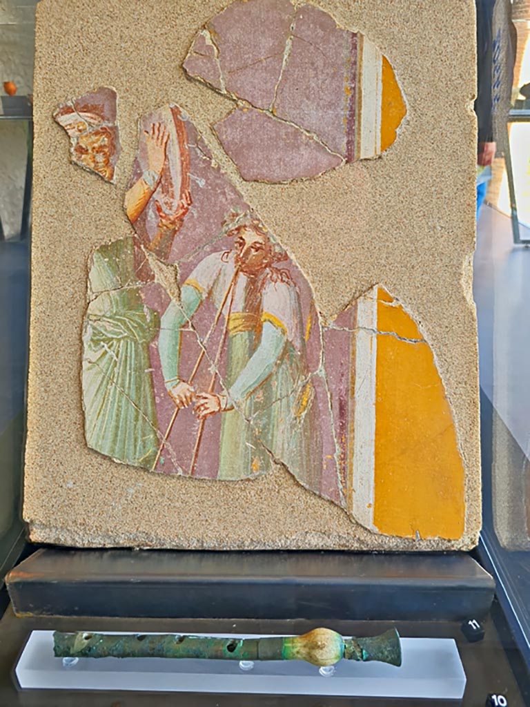 Insula Occidentalis, Pompeii. March 2024. Photo courtesy of Giuseppe Ciaramella
No.11, fresco with travelling musicians. (Ist century AD). (Affresco con musici ambulanti (I sec. d.C).
On display in exhibition in Palaestra entitled – “L’altra Pompei, vite comuni all’ombra del Vesuvio”.
No.10 below, flute made of bone and sheet bronze. (Ist century AD), from I.12.6.
