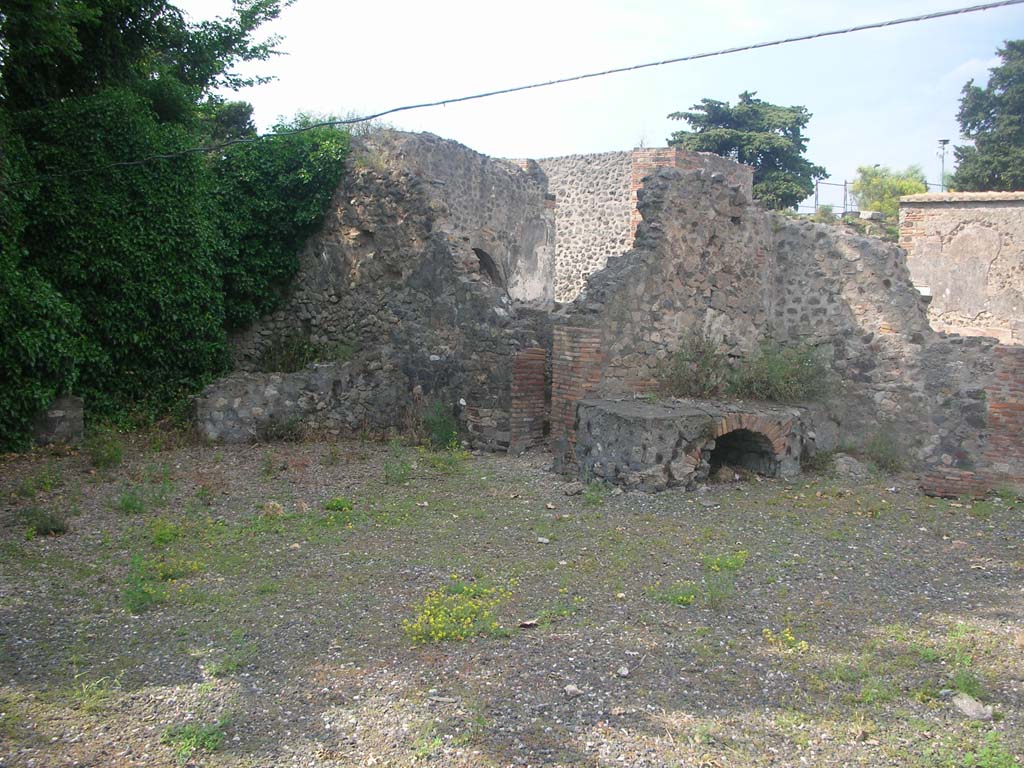 VI.17.1 Pompeii. May 2010. 
Looking north-east towards doorway to small room, latrine or corridor near east wall, in centre, and hearth in kitchen against north wall.
Photo courtesy of Ivo van der Graaff.
