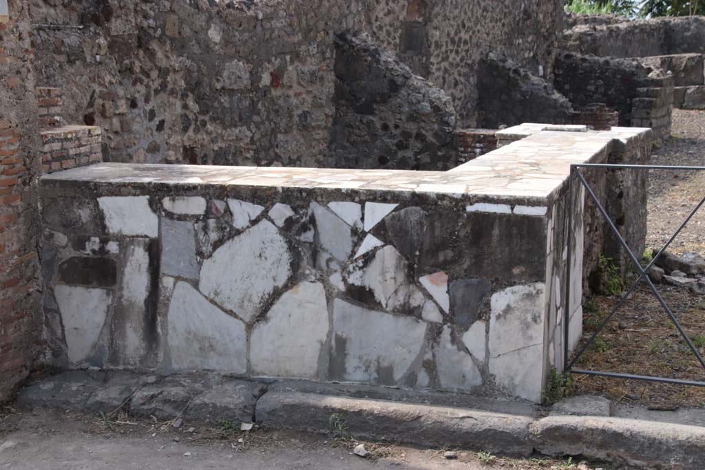 VI.17.4 Pompeii. September 2021. 
Looking west along south wall with two-sided marble counter with hearth and display shelves. Photo courtesy of Klaus Heese.