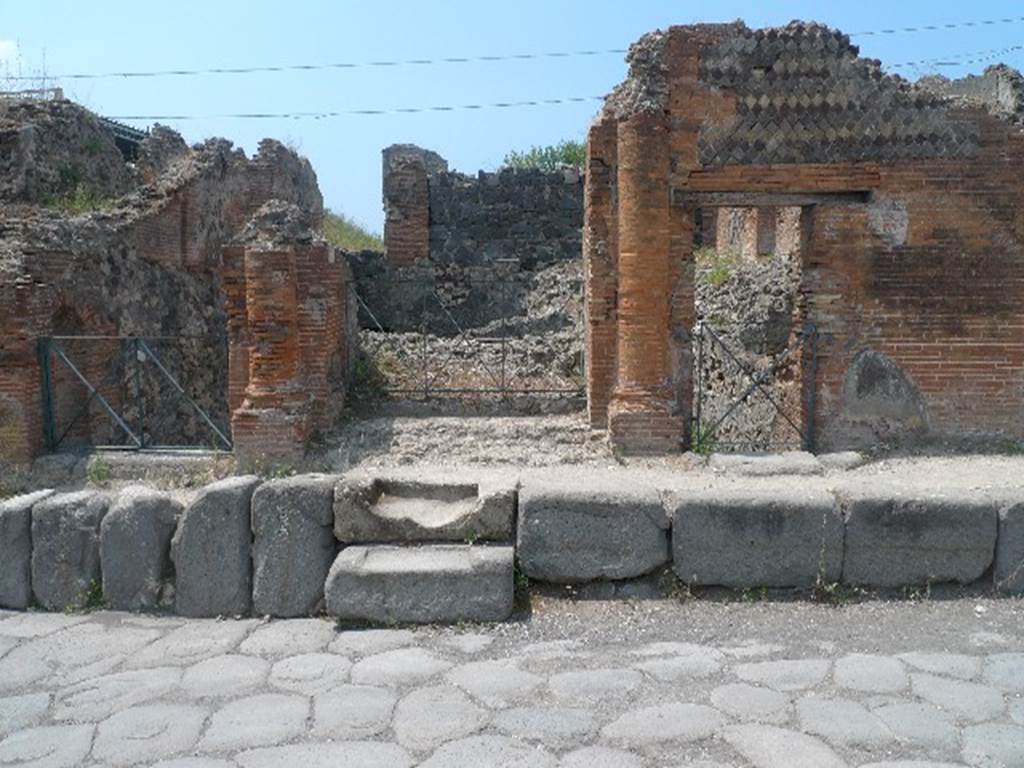VI.17.36 Pompeii. July 2010. Looking west to entrance doorway with a brick half round column on each side. Photo courtesy of Michael Binns. According to Fiorelli –
“VI.17.32-38. L’ingresso principale del caseggiato anzidetto e dal no.36, essendo un adito minore quello che porta il no.32. In entrambi sonovi scale per accedere ad un piano piu elevato dal livello della strada, ove trovansi situati due atrii, ambo uscenti nel peristilio di uno spazioso giardino, circondata da piu stanze. Vi stavano due gradinate, piu cubicoli, un triclinio con apotheca a fianco, e nel mezzo del giardino una vasca con scalini per scendervi dentro.” Altre botteghe, ed una gradinata per cenacoli independenti, furono pure scoperte, che ora trovansi nuovamente sottera.
See Fiorelli, G. (1875). Descrizione di Pompei, (p.434)
See Pappalardo, U., 2001. La Descrizione di Pompei per Giuseppe Fiorelli (1875). Napoli: Massa Editore. (p.159).
(translation - “The main entrance to the aforesaid house was by entrance number 36, having a secondary doorway entrance that carried the number 32. In both of these doorways, there were stairs to access a higher level from the street, where two atriums were located, both opening into the peristyle of a spacious garden, surrounded by many rooms. There were two flights of steps, more cubicula, a triclinium with small room/apotheca alongside, and in the middle of the garden a basin/pool with steps to go down inside. (VI.17.37 and 28. “Other shops, and steps to an independent living area, were also discovered, which now again have been reburied under the earth.” (These have since been re-excavated)