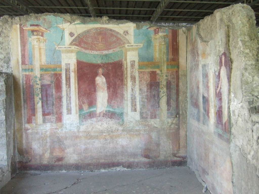 VI.17.41 Pompeii. May 2006. Exedra on north side of cubiculum. Looking east towards architectural paintings of robed figures.
The flooring was of a carpet mosaic of black tesserae with regular dots of white tesserae, flakes and tiles of alabaster and polychrome marble arranged in a very sparse basket weave: the border was of white tesserae.