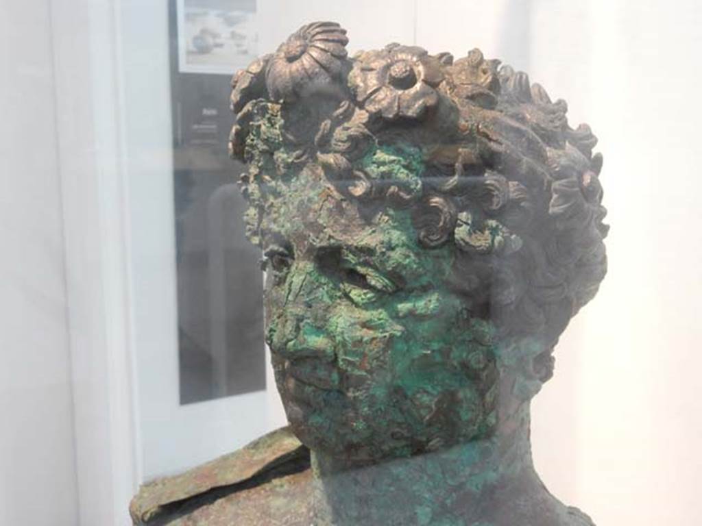 VII.16.17-22, Pompeii. May 2018. Detail of Bronze Herm discovered at Insula Occidentalis.
The hair is made up of a dense mass of short curls and a thin crown adorned with flowers.
Photo courtesy of Buzz Ferebee.
Now in Boscoreale Antiquarium and Museum, inventory number: 13441.