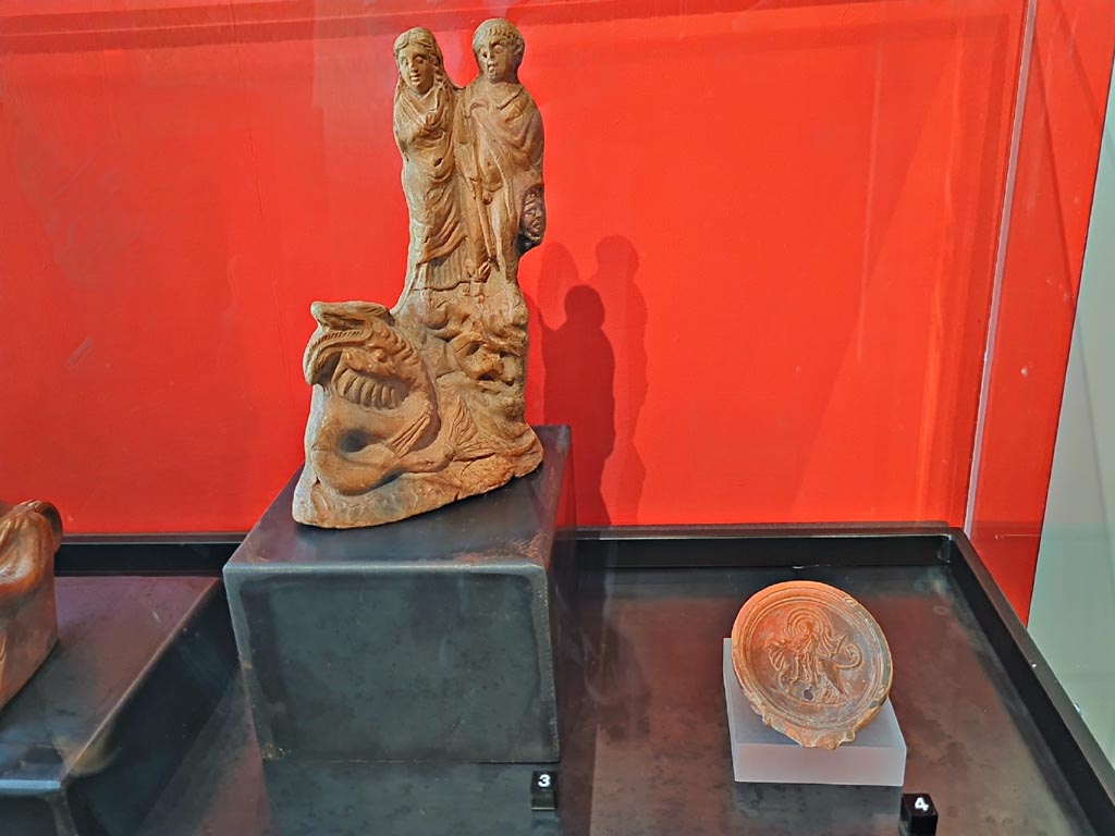 VII.1.8 Pompeii. March 2024. Photo courtesy of Giuseppe Ciaramella.
No.4 (on right) – Oil lamp depicting the Rape of Europa (1st century AD). (Lucerna con Europa rapita dal toro (I sec. d.C).)
Provenanced to the Stabian Baths, but we do not know the exact find location.
On display in exhibition in Palaestra entitled – “L’altra Pompei, vite comuni all’ombra del Vesuvio”.