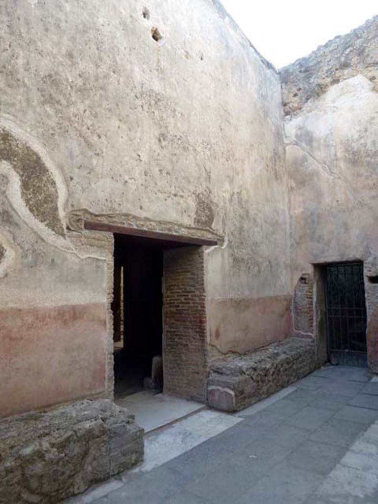 VII.1.8 Pompeii. June 2012. Looking north-west across men’s waiting room 2a and stone benches. The large doorway in the centre of the west wall leads into changing room 2. The smaller gated doorway in the north wall leads into the narrow rooms 2b, 2c and VII.1.15. hoto courtesy of Michael Binns.