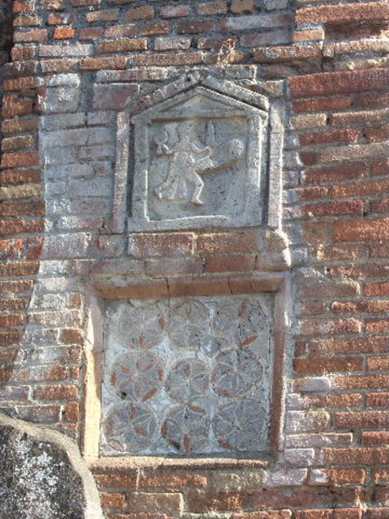 VII.1.36 Pompeii. September 2005. Ithyphallic and geometric plaques outside VII.1.36 Modestus Bakery, on pilaster on east side of entrance doorway.