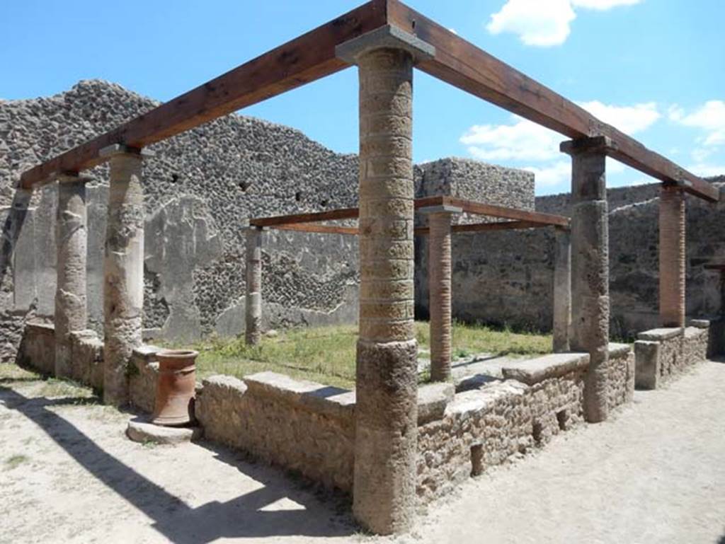 VII.1.47 Pompeii. May 2017. Looking south-east across peristyle 19. Photo courtesy of Buzz Ferebee.
According to Jashemski –
The peristyle garden at the rear of the tablinum of the house at entrance 47  was enclosed on the west and north by a portico supported by five columns which were joined by a low wall, with an entrance to the garden on the west.
Both the mouth of a cistern (on the north) and a terracotta puteal (on the west) were incorporated into the low wall.
The four small columns in the garden probably supported a pergola which shaded a wooden triclinium.
See Jashemski, W. F., 1993. The Gardens of Pompeii, Volume II: Appendices. New York: Caratzas. (p.169-71.
According to Soprano –
Ubicazione: giardino.
Bibliog. Fiorelli, op. c, p.180; idem Scavi di Pompei dal 1872, p.12;
Breton, op. c. p.317; Overbeck, op. c, p.286.
Al centro del giardino s’innalzavano quattro piccole colonne che probabilmente sostenevano il pergolato di letti tricliniare in legno.
See Soprano, P. (1950). I triclini all’aperto di Pompei. (In Pompeiana, raccolta di studi per il secondo centenario degli scavi di Pompei. Napoli, Gaetano Macchiaroli, Editore, P. 308, no.34).