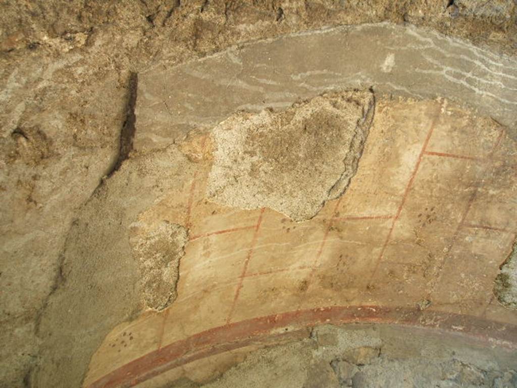 VII.2.7 Pompeii. Shop. May 2005.  Small remains of painted plaster in arched niche under masonry staircase on north wall. The arch was outlined in red on a white background with a dotted rosette in each of the painted squares.