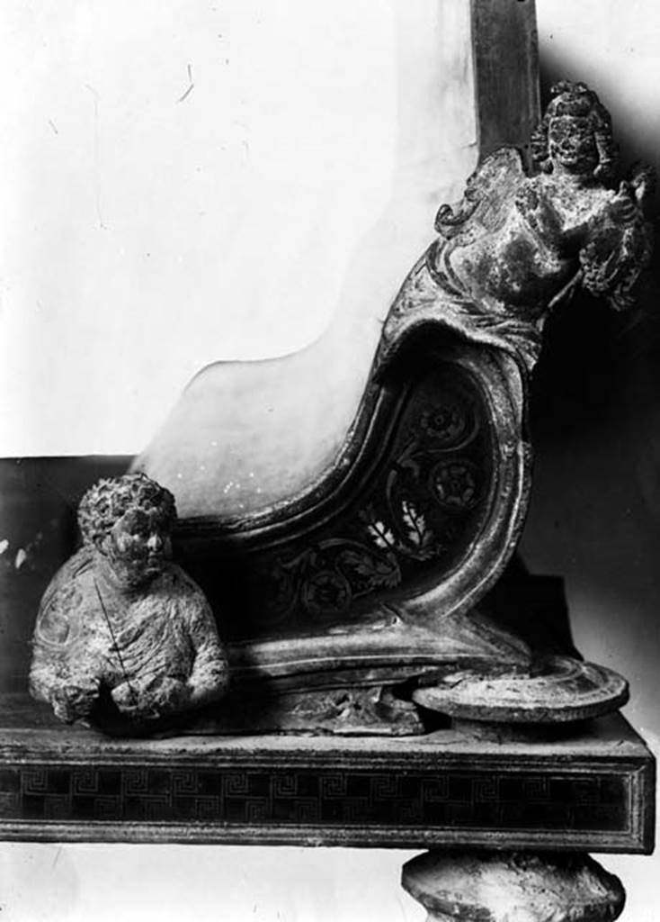 231807 Bestand-D-DAI-ROM-W.0007.jpg
VII.2.18 Pompeii. W.7. Detail from end of dining couch, bronze inlaid with silver. According to Breton, found on January 11th 1868, were a total of three large and magnificient dining couches. At that time, the marks where their feet had stood could still be seen in the soil. They were made of wood and bronze, inlaid with silver and copper. The wood was not preserved but could be reconstructed from the impression left in the ash. One of the couches was on display at the Museum of Naples. Near the couches were remains of pieces of bread, two large candelabra, a lamp, a bucket, a beautiful lantern surmounted by a figure of Pan, two strigils, vases and cups of bronze, and a bronze bracelet in the shape of a serpent with eyes made from small emeralds.
See Breton, Ernest. 1870. Pompeia, Guide de visite a Pompei, 3rd ed. Paris, Guerin. 
Photo by Tatiana Warscher. With kind permission of DAI Rome, whose copyright it remains. 
See http://arachne.uni-koeln.de/item/marbilderbestand/231807