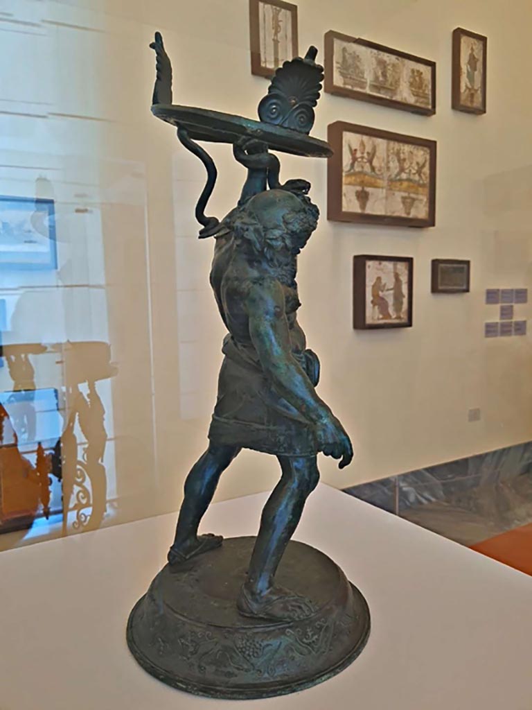 VII.2.20 Pompeii. October 2023.
Side and rear view of bronze statuette of Drunken Silenus. Photo courtesy of Giuseppe Ciaramella. 
On display in “L’altra MANN” exhibition, October 2023, at Naples Archaeological Museum, inv. 5001.