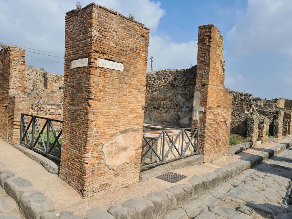 VII.2.33 Pompeii. October 2023. Looking north to entrance doorway on north side of Via degli Augustali, in centre. 
On the left is the other entrance at VII.2.32 in Vicolo Storto. Photo courtesy of Klaus Heese.