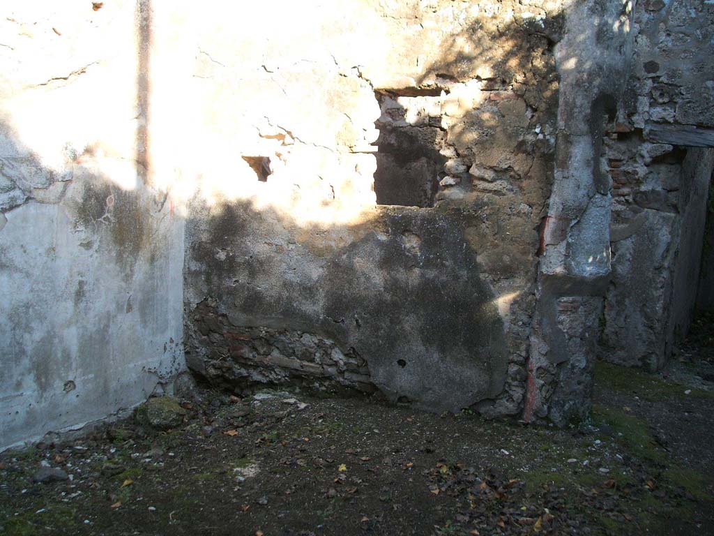 VII.2.48 Pompeii. December 2004. 
Looking towards the east wall of the garden area, with window and doorway opening into a corridor at the rear of the house.
The walls were covered with simple rough plaster, and a column of the portico has been incorporated into the wall.