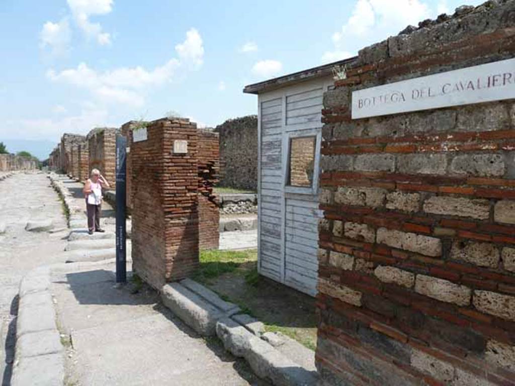 VII.3.14 Pompeii. May 2010. Entrance to shop, looking east across Via Stabiana towards Via di Nola with Bottega del Cavalieri sign.
The tavern (VII, 3, 14-15) was one of the stops of the visit of Pope Pius IX on October 22, 1849, and from where was found, together with a lot of bronze materials and marble fragments, the bas-relief of the galloping cavalier (Museo Profano, Bib. Apostolica Vaticana, inv. 4092), of which there has been much debate about its true Pompeian origin, in a controversy that does not even seem settled after the study made by Conticello (AA.VV., 1987: 31-38, tav. 2) for the catalog of the exhibition twenty years ago dedicated to this visit.
See Uroz Sáez J., Uroz Rodríguez H., 2008. Pompeya: Regio VII, Insula 3. Instituto del Patrimonio Cultural de España, p. 60.