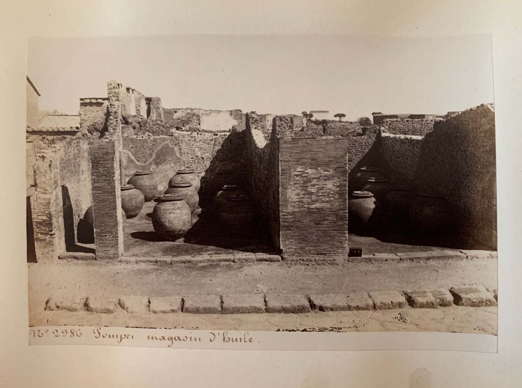 VII.4.13, in centre left, and 14, in centre right. 
Album by M. Amodio, c.1880, entitled “Pompei, destroyed on 23 November 79, discovered in 1748”.
According to the writing on this photo, this was a warehouse (storehouse) for oil. Photo courtesy of Rick Bauer.