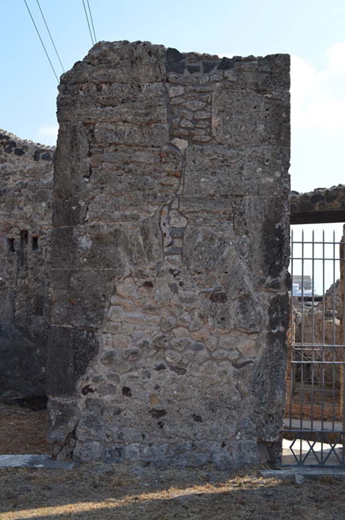 VII.4.31/51 Pompeii. September 2019. 
Pilaster on east side of atrium, with filled in niche, between doorways to room 9, and entrance doorway into room 10, leading to VII.4.33, on right.
Foto Annette Haug, ERC Grant 681269 DÉCOR.
(Note: our numbers are different to other plans, 
- PPM would indicate a pilaster between rooms 10 and 11,
- Descoeudres used the same numbering).
According to Descoeudres – in the atrium “above this high marble veneered dado, the walls were painted.  
None of the paintings are extant, but the 19th century excavation notes mention one of them which at the time was still to be seen.  
It is described as “a bizarre frieze showing the carriage of Bacchus (or Dionysus) with 2 panthers yoked to it, and on either side garlands of grapes against which 2 ladders rest with 2 cupids climbing up”.
(In the archive of NAP there is a water colour tracing which obviously depicts half of this frieze. (Fig 40, page 69). One can see that the carriage contained a mask of Dionysus and not Dionysus himself.  Since it is a tracing it is at actual size and it is clear that the full frieze, which must have been the border of a large panel must have been at least 1.5m wide.  There are not many long stretches of wall in the atrium which was surrounded by many entrances and doors, and the only wall in the atrium at the time of excavation that was long enough to accommodate such a large panel was that between rooms 10 and 11.  
Closer examination of this wall also reveals a niche, which at some stage was badly damaged (by earthquake?).  
The vertical crack which can still be seen is typical of earthquake damage). The wall was later repaired and the niche filled in.  
This was probably the site of the original Lararium – this is usually located in the atrium, but in this house it is located in the west ala (7). (Note: our room 6).  
It was probably moved there after the earthquake, probably after 62AD. 
The wall where it had originally stood was then repaired and covered with marble veneer.  
If this interpretation is correct, then the application of marble veneer to the atrium walls must have been done after 62 AD.”
See Descoeudres J-P., Ed., 1994. Pompeii Revisited: The life and death of a Roman town. Sydney: Meditarch, (p.70-71).