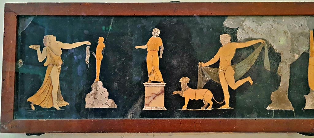 VII.4.31/51 Pompeii. 
Found in tablinum on 22nd May 1845. Dionysian scene in coloured marble. Photo courtesy of Giuseppe Ciaramella. September 2024.
Now in Naples Archaeological Museum. Inventory number 9979.  
According to information card –
Dionysian scene. Slate wall panel with polychrome marble inlay work.
A statue on a pedestal is depicted in the centre of the scene; Dionysus, dressed in a cloak, is dancing on the right, preceded by a panther; on the left, a Maenad, who is also dancing, brings offerings to a statue of Priapus, placed on a rock. (Third quarter of the Ist century AD).
(Scena dionisiaci. Panello parietale di ardesia con intarsia marmorei policromi.
La scena raffigura, al centro, una statua su piedistallo; Dioniso con mantello danza, da destra, preceduto da una pantera; mentre da sinistra, una Menade pure danzante reca offerte alla statua di Priapo, posto su una roccia. Terzo quarto del I secolo d.C.)