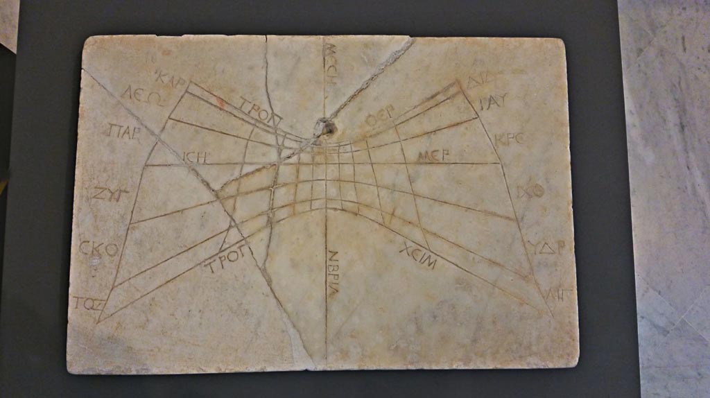 VII.4.57 Pompeii. November 2018. According to the information card –
“The sundial was discovered at Pompeii on 14th July 1837 in the House of the Figured Capitals.
The dial consists of a portion of an oblique circular cone. 
The lower curve corresponded to the dates of 30 April and 12 August since the dial erroneously terminates before the extension it ought to have had to capture the shadow cast by the gnomon at the summer solstice.
There are 11 engraved hour lines: in accordance with the standard layout, the lines are made by joining the edges of the 12 respective parts into which the three day curves are divided.”
On display in Naples Archaeological Museum.  Photo courtesy of Giuseppe Ciaramella.