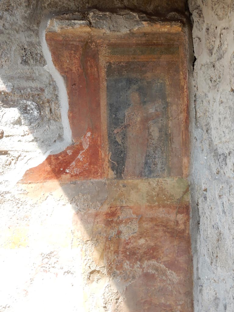 VII.7.5 Pompeii, May 2018. Oecus (m), west wall in north-west corner. 
It is just possible to glimpse a female figure holding a plate of offerings in her left hand, on the black panel.
This would have been above a high zoccolo with panels of false painted marble.
See Sogliano, A., 1879. Le pitture murali campane scoverte negli anni 1867-79. Napoli: Giannini. (no.793)
Photo courtesy of Buzz Ferebee.
This would have been to the north of the doorway opening onto the east portico.