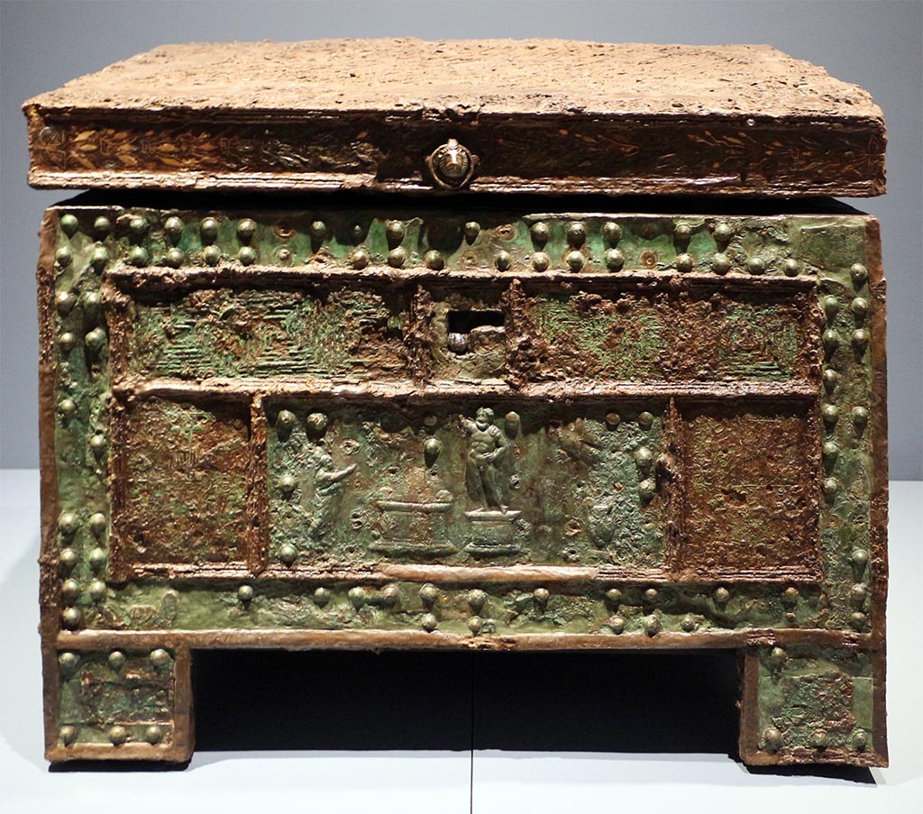 VII.7.5 Pompeii, Found 29 October 1864, now in Naples, Museo Archeologico Nazionale, (inv. 73020).
“Arca”/strong-box with Sacrifice to Jupiter, after restoration, made of wood, with iron and bronze coating; copper bronze and tin.
Photo “Restituzioni  2016” courtesy of Sailko, <CC BY 3.0>, via Wikimedia Commons.
The strong-box/safe with an offering to Jupiter was discovered in Pompeii on 29 October 1864 in the House of Triptolemus (VII.7.5) 
According to Fiorelli –
…ed immette nell’atrio tuscanico, ove la cassa di ferro pel domestico peculio stava situata sopra un grande pezzo di travertino, ch’e a sinistra della porta d’ingresso: delle sue dipinture rimangono sei Amorini, tutti portanti in mano un corno d’abbondanza.
(trans: “and leads into the Tuscan atrium, where the iron chest for domestic money was placed on a large piece of travertine, which is on the left of the entrance doorway: of its paintings (in the atrium) remain six Cupids, all carrying in their hand a horn of abundance.”)
See Pappalardo, U., 2001. La Descrizione di Pompei per Giuseppe Fiorelli (1875). Napoli: Massa Editore. (p.98)
See Fiorelli, G., 1875. Descrizione di Pompei. Napoli, (p.242).